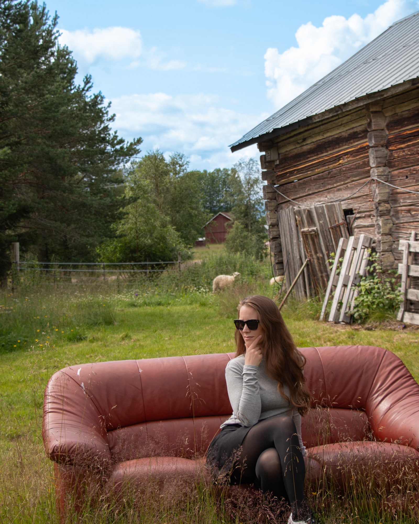 Lisah Silfwer i solglasögon på en röd soffa vid en lada.